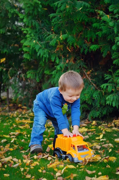 Joyful baby boy in autumn park playing machine — Stock Photo, Image