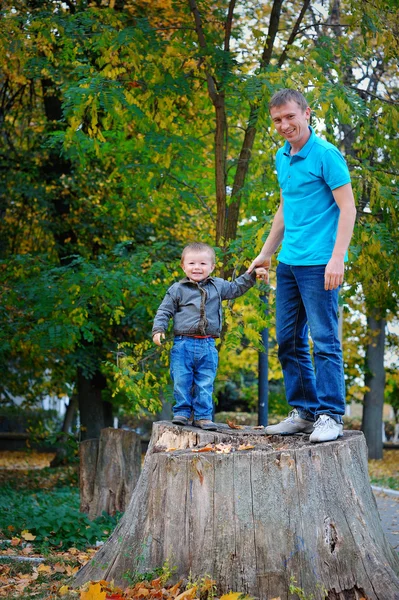 Padre e hijo de pie sobre un muñón en el parque — Foto de Stock