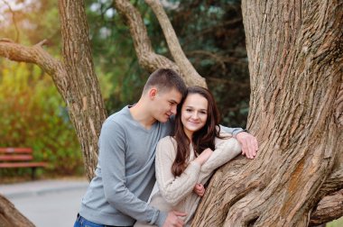 Genç bir çift yeşil parkta flört. Kız holding telefon gidiş