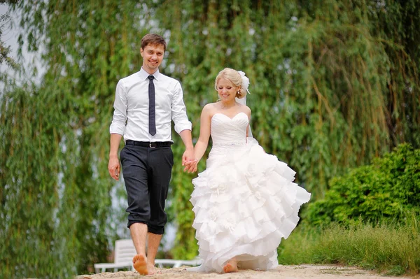 Novia y novio caminando descalzos en la playa — Foto de Stock