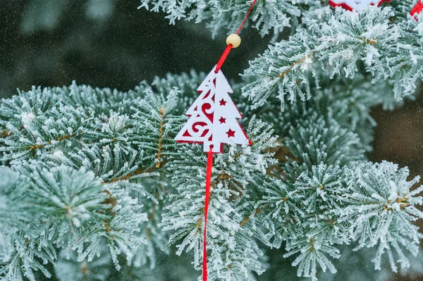 Hintergrund schneebedeckter Weihnachtsbaum mit rotem Weihnachtsbaum-Spielzeug aus — Stockfoto