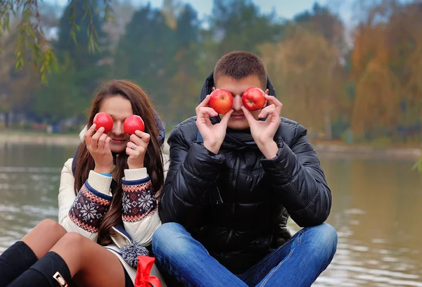 Pareja feliz en el jardín de otoño.Divirtiéndose en la hierba y comiendo — Foto de Stock