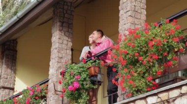 Sevgi dolu babası ve kırmızı çiçekli Balkonda duran kadın