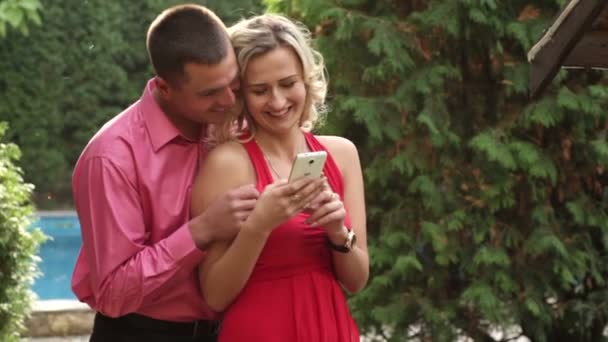 Пара влюбленных в парке с телефоном — стоковое видео