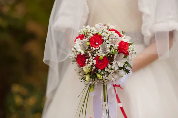 Bridal bouquet of red roses in bride's hands — Stock Photo, Image
