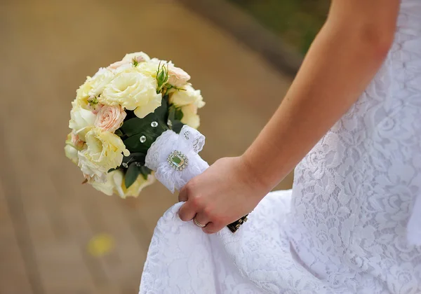 Bride sitting on bench holding wedding bouquet of various flower — Stock Photo, Image