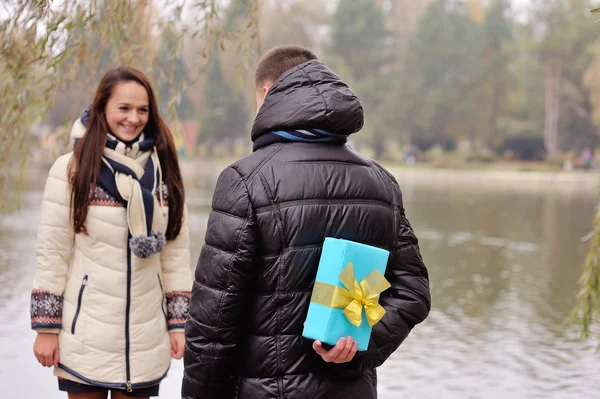 Hombre da a una mujer un regalo al aire libre — Foto de Stock