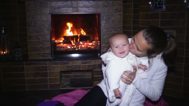 Mom plays with her daughter near a fireplace — Stock Video