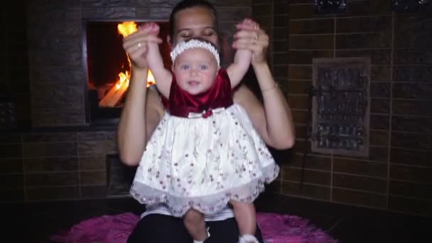 Mom plays with her daughter near a fireplace — Stock Video