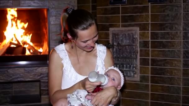 Mother feeds the child from the bottle by the fire — Stock Video