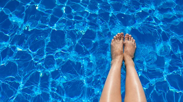 Pernas menina em um fundo de água da piscina — Fotografia de Stock