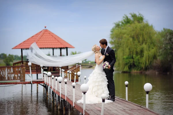 Bride and groom kissing on a bridge — Stock Photo, Image