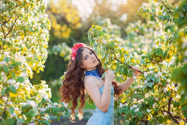 Mulher bonita em um parque de primavera com uma grinalda na cabeça — Fotografia de Stock