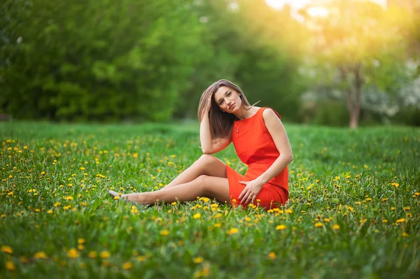 Schöne Frau sitzt auf einem Feld von Löwenzahn — Stockfoto