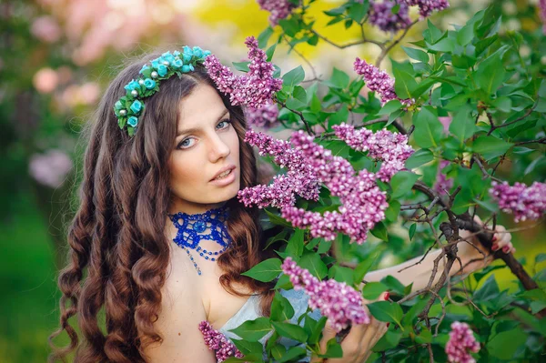 Schöne Frau im Frühlingsgarten mit einem Kranz aus Flieder — Stockfoto