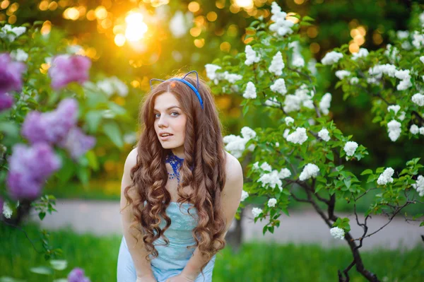 美丽的女人，在郁郁葱葱的花园在春天紫丁香 — 图库照片