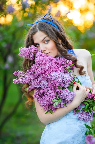 Bela mulher com um buquê de lilases na primavera — Fotografia de Stock