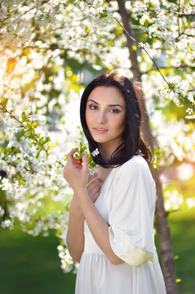 Bella ragazza nel giardino primaverile tra gli alberi in fiore con pi — Foto Stock