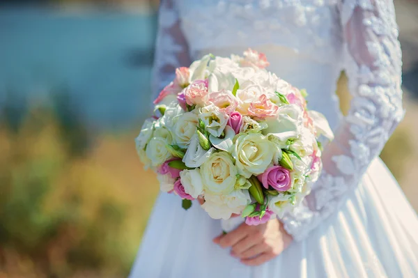 Braut in einem weißen Kleid im sommergrünen Park mit einem Strauß in — Stockfoto