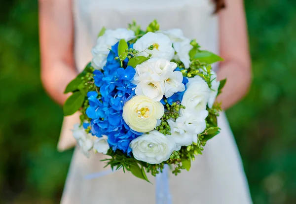 Bouquet de mariée bleu avec des fleurs blanches dans les mains de la mariée — Photo