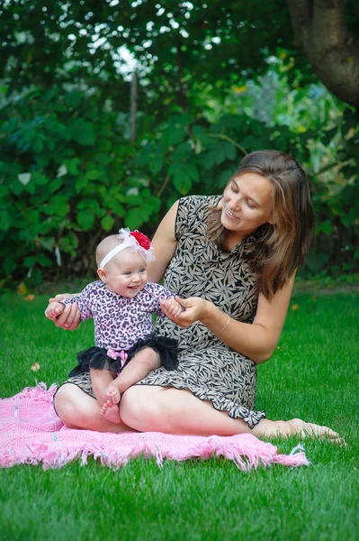 Junge Mutter mit kleiner Tochter spielt im Park — Stockfoto