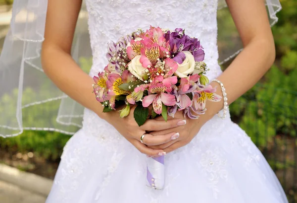 Brautstrauß aus lila Blumen in den Händen der Braut — Stockfoto