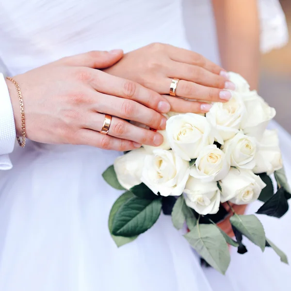 Manos de la novia y el novio con anillos de boda en el ramo — Foto de Stock