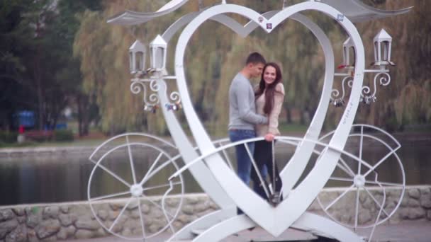 Loving couple standing in the gazebo in the form of heart in the park — Stock Video