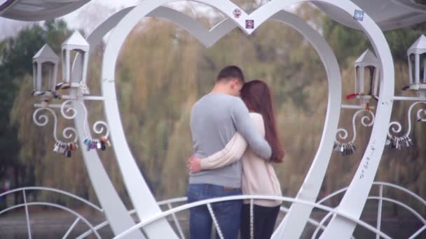 Loving couple standing in the gazebo in the form of heart in the park — Stock Video