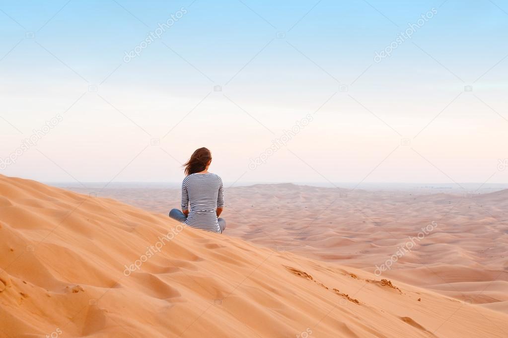 woman watching the sunset in the desert sand
