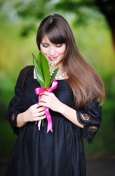 Woman with a bouquet of lilies of the valley in the spring park — Stock Photo, Image