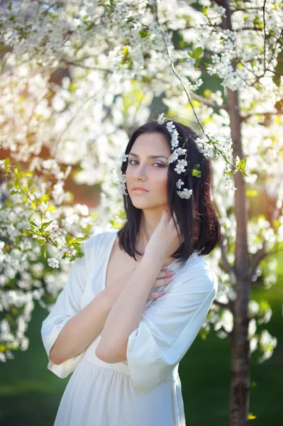 Mujer con una corona de rosas en la cabeza en el jardín florecido —  Fotos de Stock