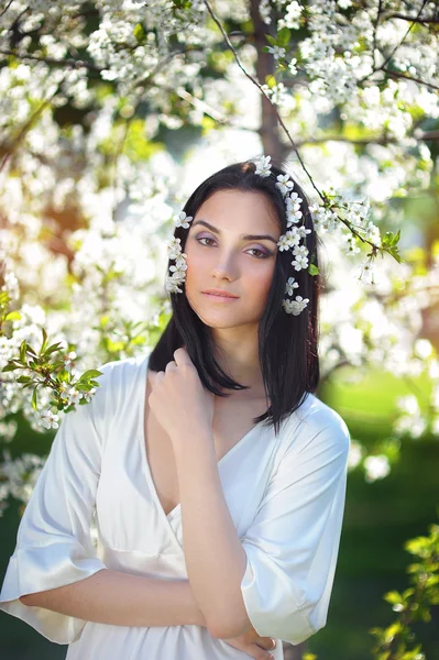 Mulher cabeluda em um parque de primavera com flores em seu cabelo — Fotografia de Stock