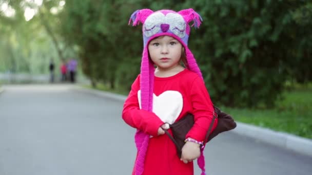 Petite fille dans un chapeau tricoté chouettes d'automne avec sac — Video