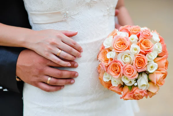 Handen van de bruid en de bruidegom met ringen op een achtergrond van een wo — Stockfoto