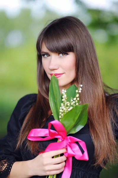 Girl with lilies of the valley in the spring in the park — Stock Photo, Image