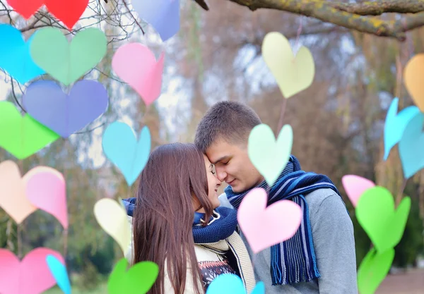 Loving man and woman in the park with the decor of hearts kiss — Stock Photo, Image