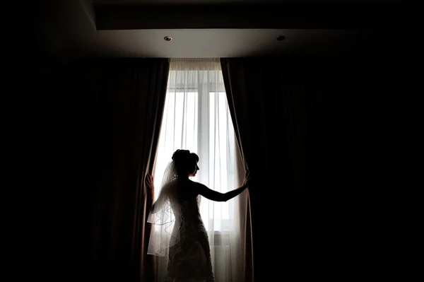 Silhouette of the bride standing at the window waiting for the w — Stock Photo, Image