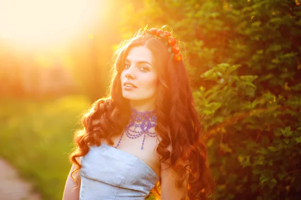 Linda menina com uma grinalda na cabeça no por do sol — Fotografia de Stock