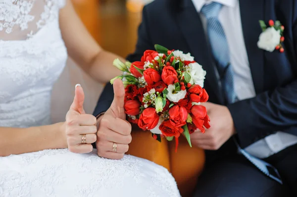 Hände des Brautpaares auf dem Hintergrund eines Hochzeitsstraußes — Stockfoto
