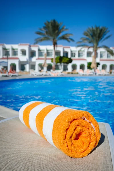 Orange towel on a sun lounger on the background of the pool — Stock Photo, Image