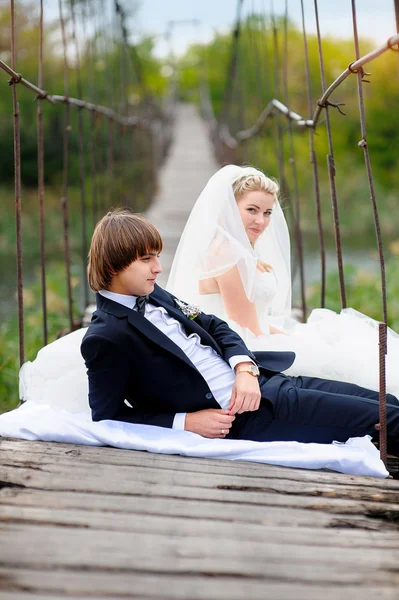 Bride groom sitting on the bridge — Stock Photo, Image