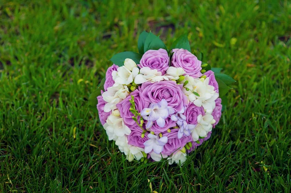 Bridal bouquet of purple roses on the grass — Stock Photo, Image