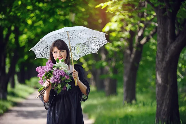 Glückliche junge Frau im Frühlingspark mit Regenschirm — Stockfoto