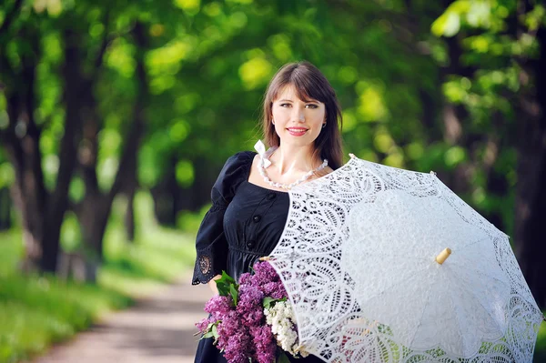 Portrait of a young woman in a spring park with an umbrella — Stock Photo, Image