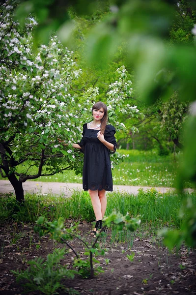 Vacker ung kvinna poserar i en blommande våren park — Stockfoto