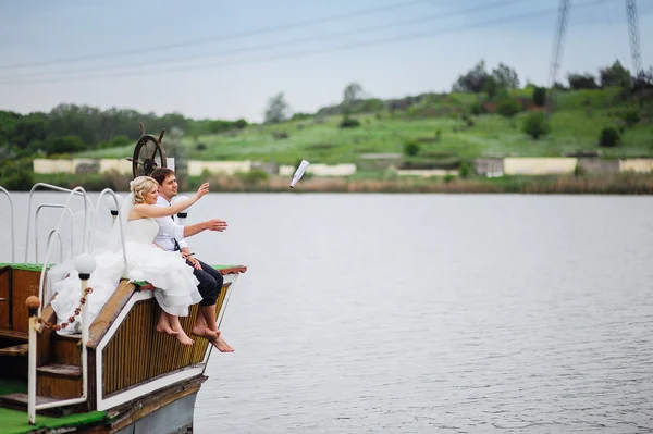 Love the bride and groom sit on the board of the ship and throw — Stock Photo, Image