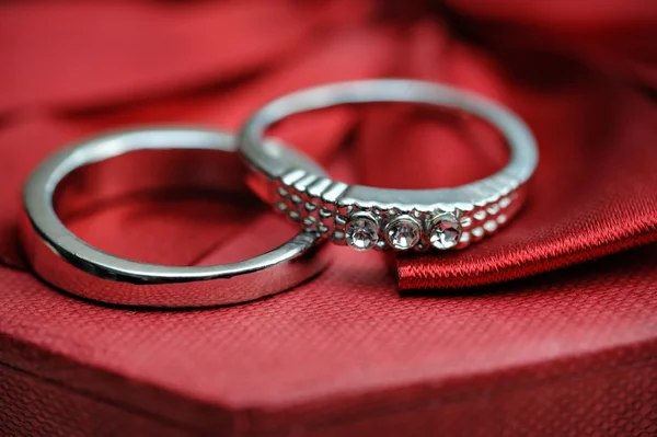 Dva snubní prsteny na červeném pozadí — Stock fotografie