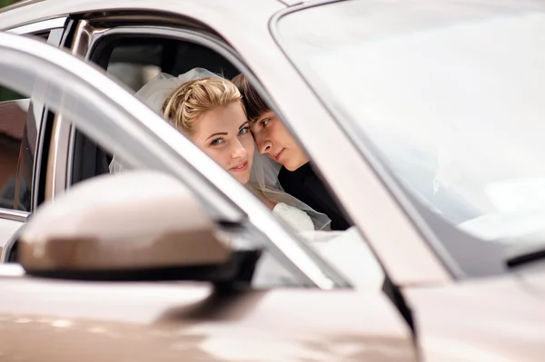 Braut und Bräutigam küssen sich im Hochzeitsauto — Stockfoto