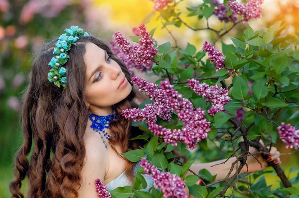 Jovem feliz cheirando um ramo de primavera de flores lilás — Fotografia de Stock